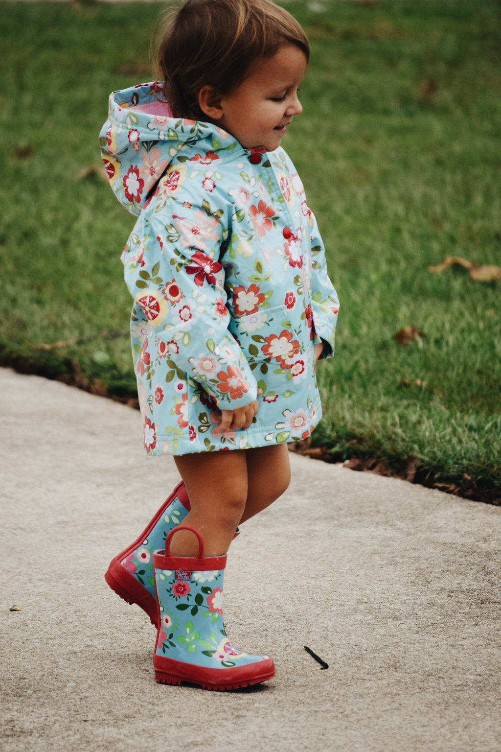 Floral light blue hooded raincoat worn by child, full zipper and side pockets