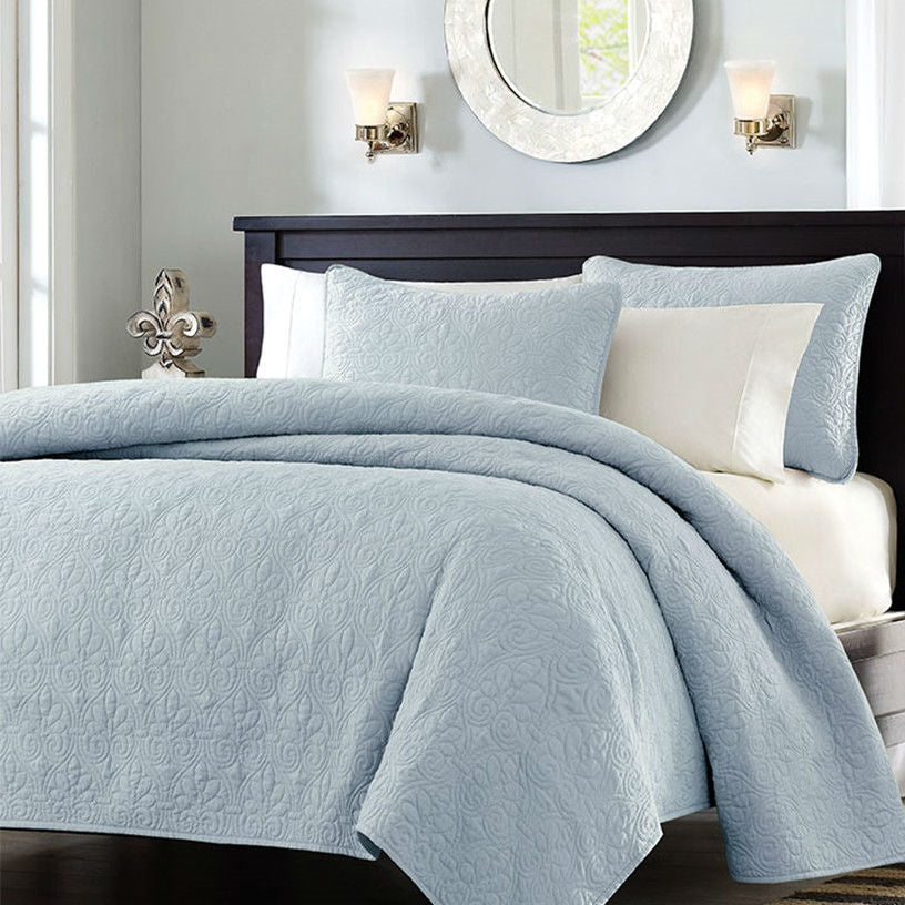 Light blue quilted bedspread with matching shams and decorative pillow