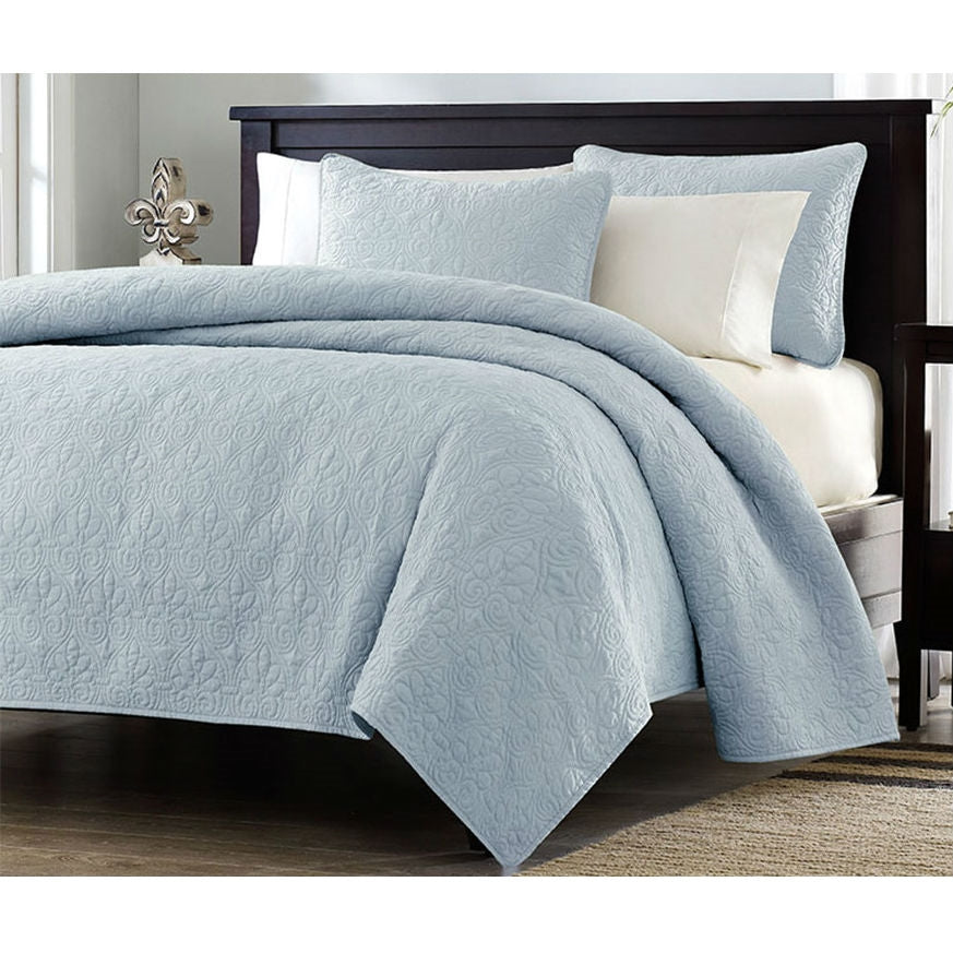 Light blue quilted coverlet set with two shams, neatly draped on bed