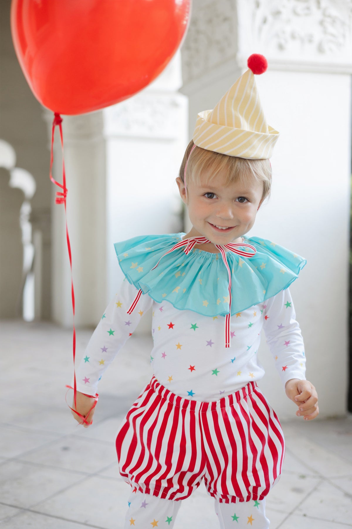 Kids clown costume: yellow striped hat, blue ruffled top, star leggings, red striped shorts