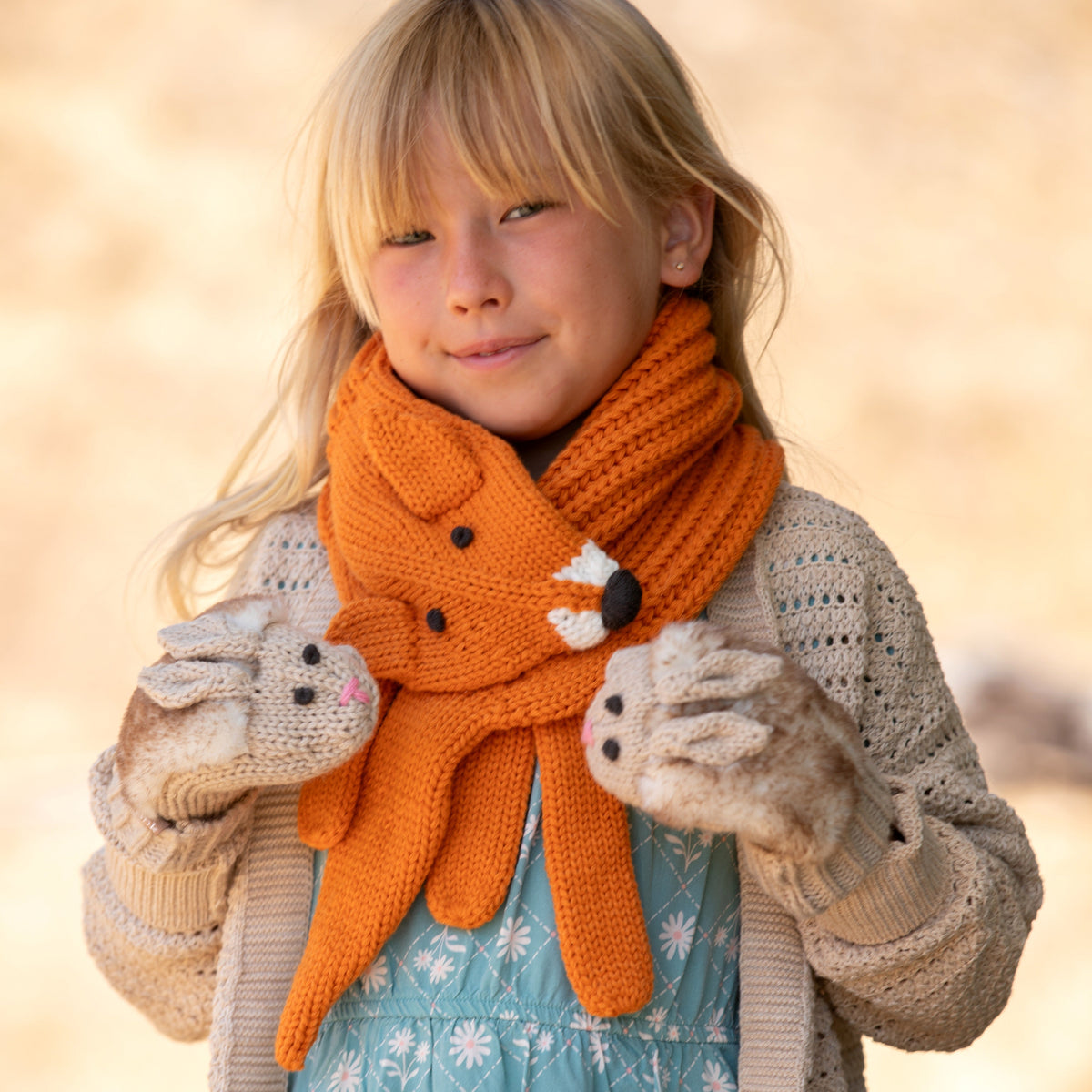 Orange fox neck scarf worn by child, with long ear ends and stitched paw detail