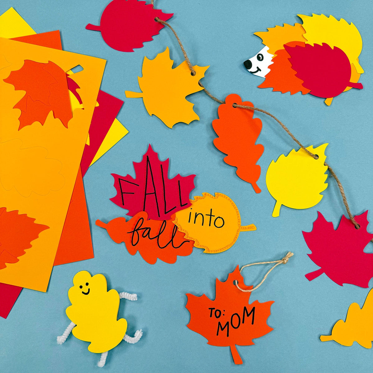 Assorted colorful fall leaf cutouts with string, ready for crafting and classroom decor