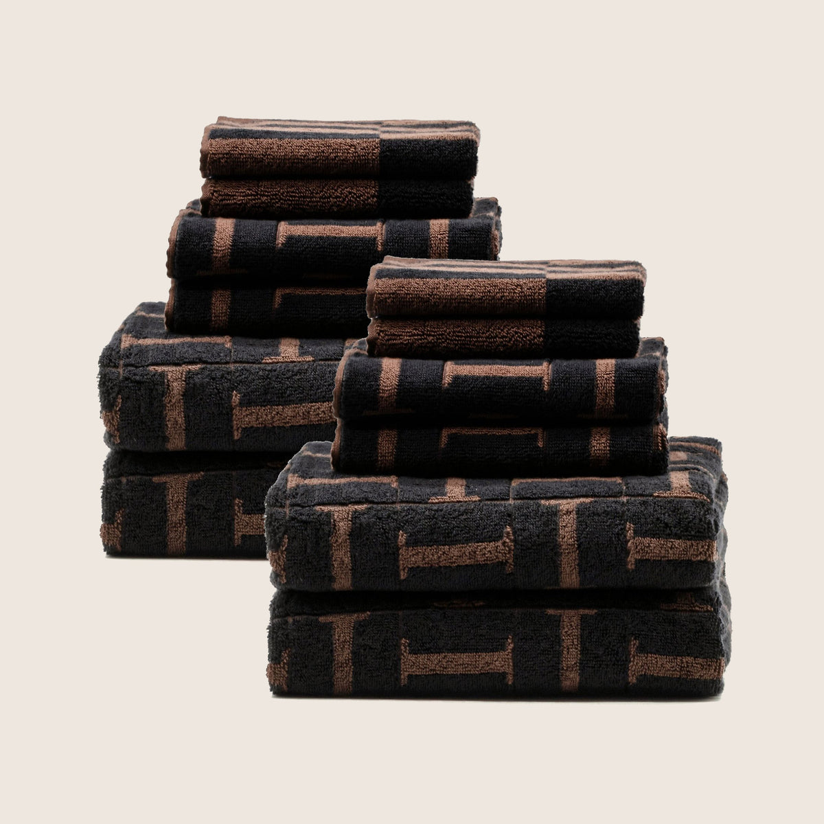 Cotton towel set in tobacco and black with woven geometric stripe bands, folded stacks