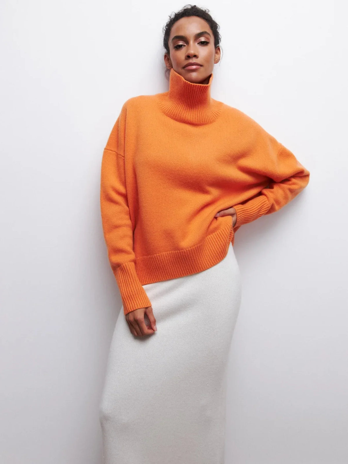 Orange knit sweater with ribbed turtleneck, long sleeves, and relaxed fit