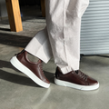 Men's dark brown lace-up leather sneakers on feet, white platform sole