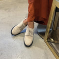 Ivory lace-up oxford shoes with perforated detail and black soles
