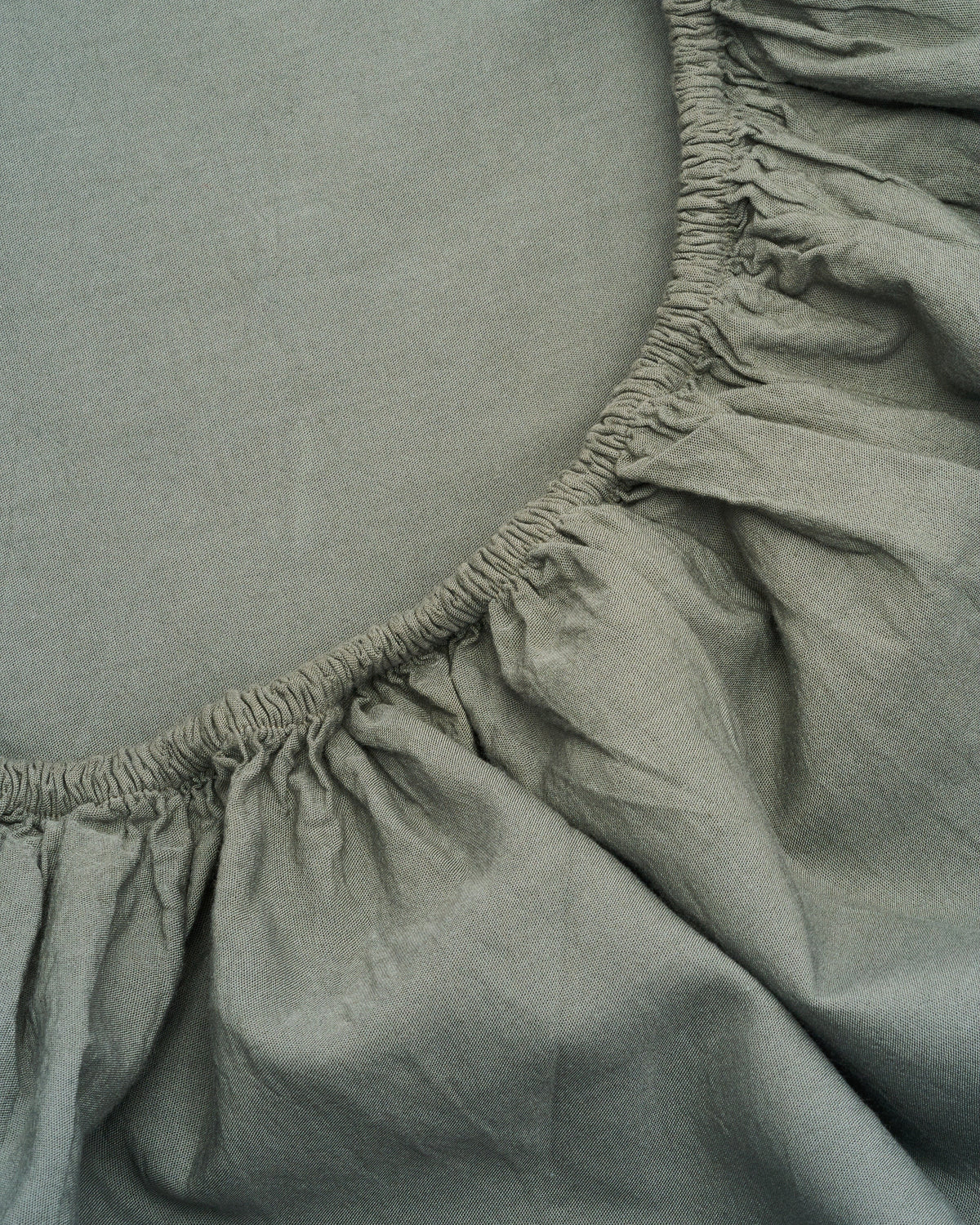 Sage sheet close-up showing elastic edge and gathered skirt ruffle