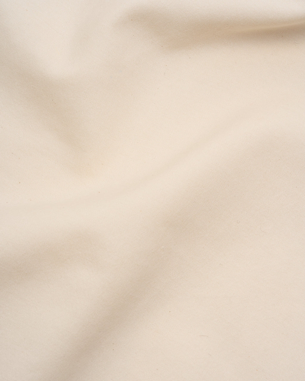 Cream bed sheet fabric close-up with subtle texture