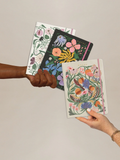 Trio notebook set with colorful botanical covers and stitched spine, hand-held view