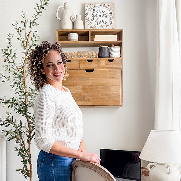 Person standing by wall-mounted fold-down wood shelf with drawers and shelves