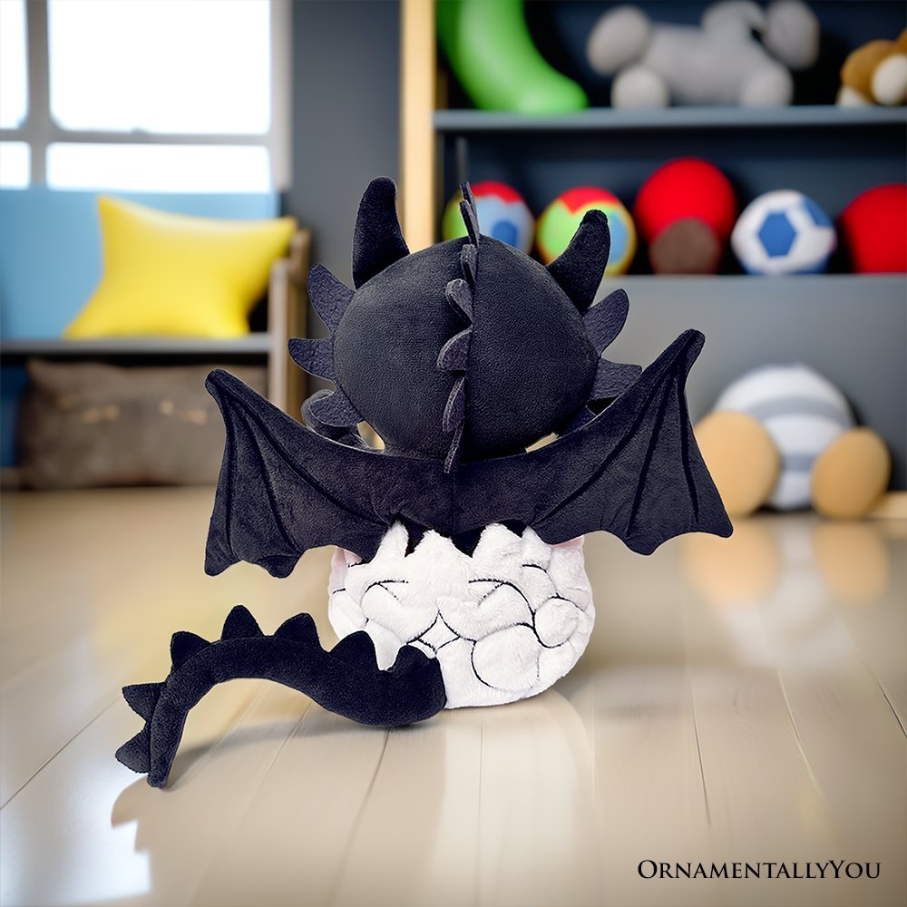Black dinosaur plush with red-ring eyes and outstretched wings, tucked into white egg plush