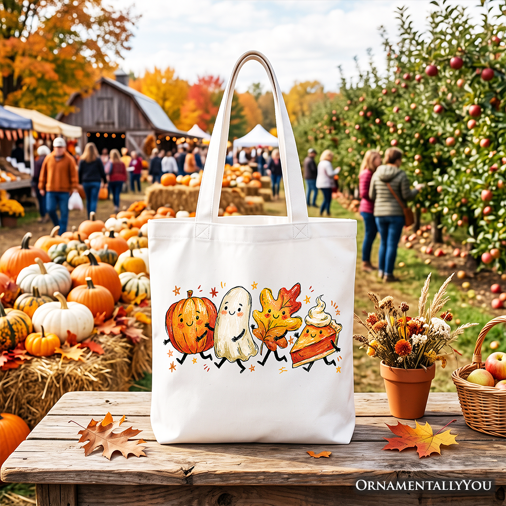 White tote bag standing upright with black handles and colorful pumpkin ghost and leaf print