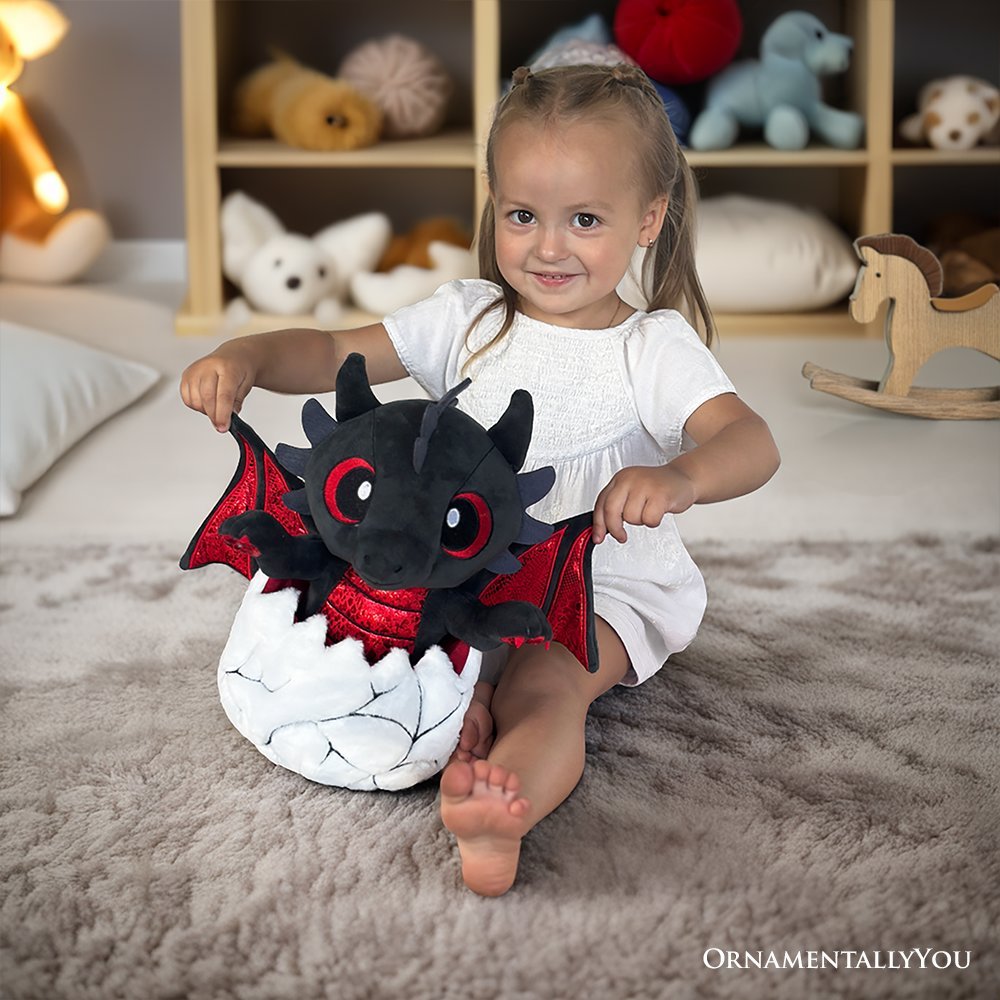 Black dinosaur plush with red wings and red eyes, sitting in a white egg-shaped base