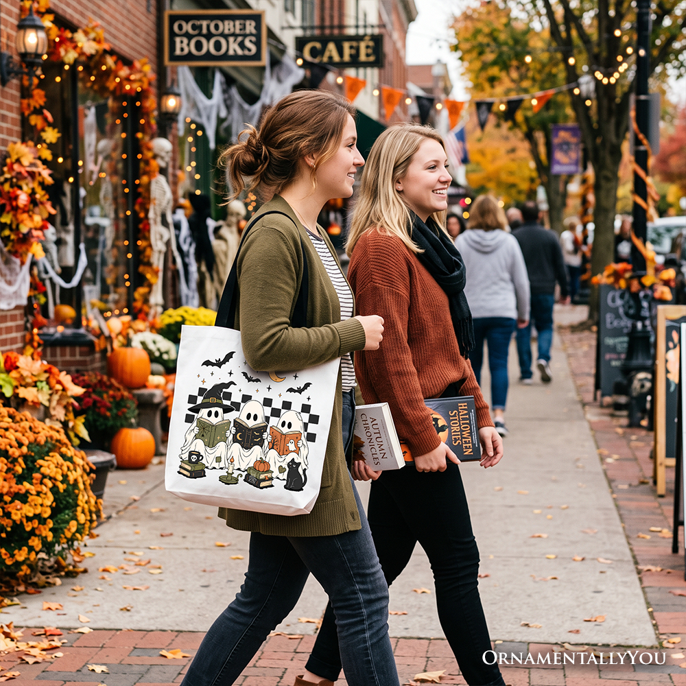 White Halloween tote bag with black ghost and witch cat print, worn by a person