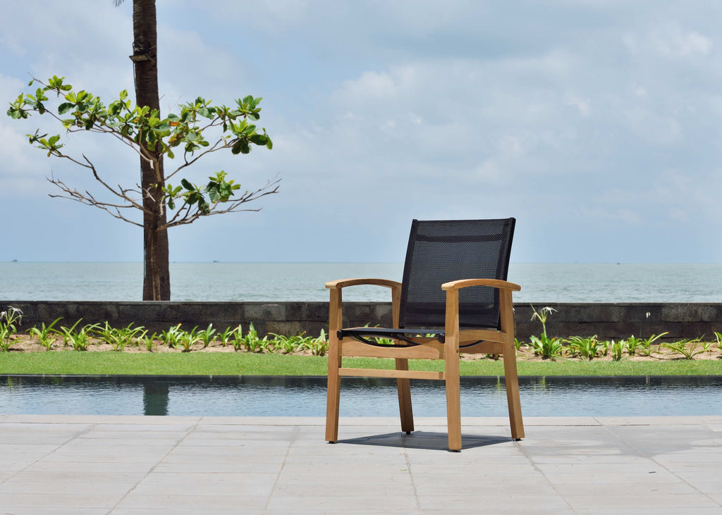 Single outdoor armchair with light teak arms and black mesh back near pool