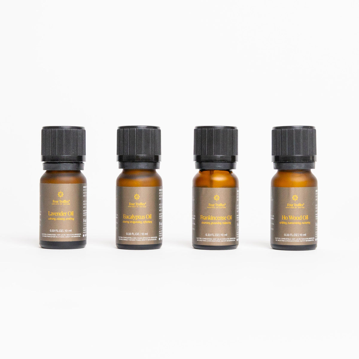 Four amber essential oil bottles with black ribbed caps on white background