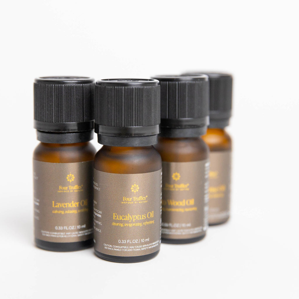 Close-up of four amber essential oil bottles with black caps and visible labels