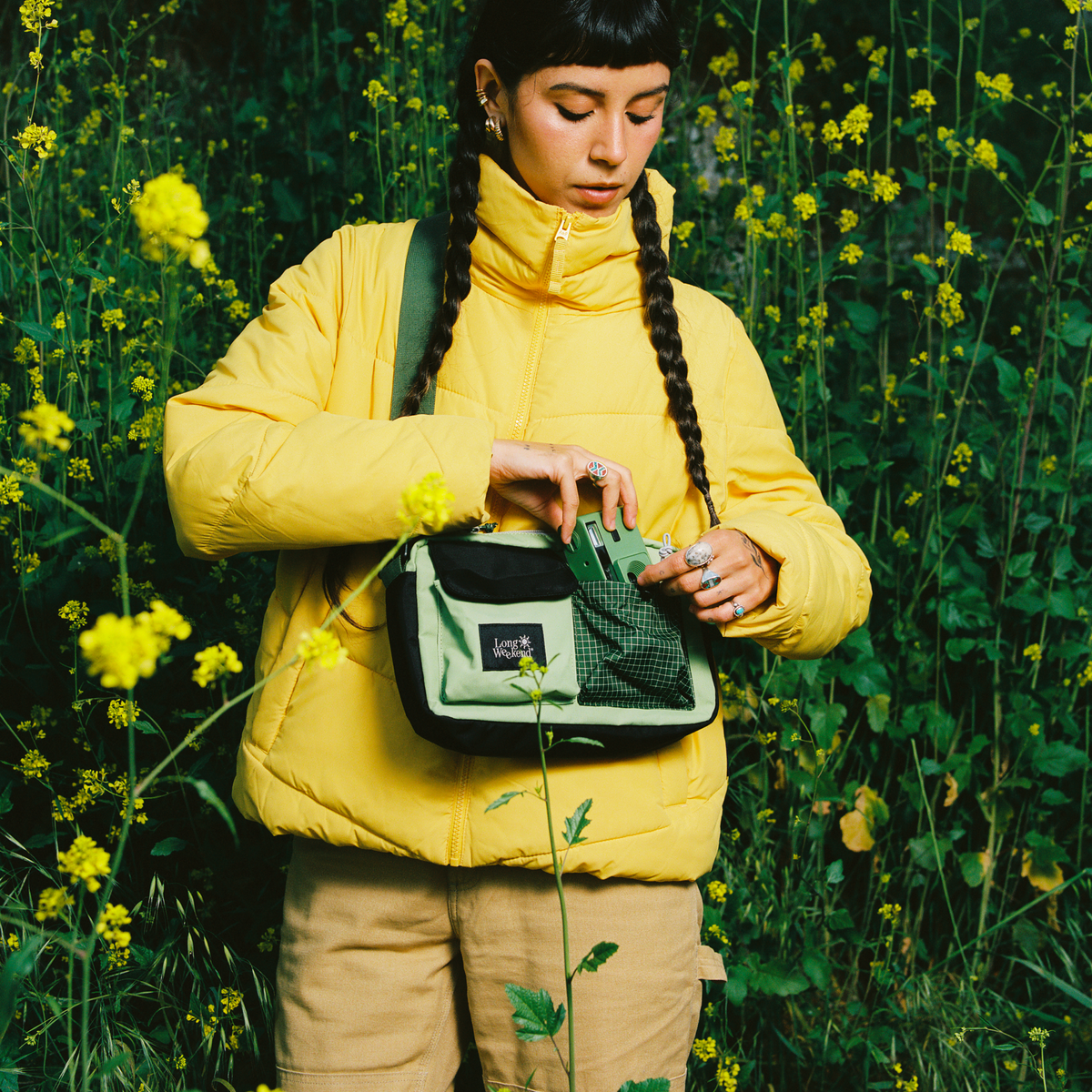 Yellow jacket and dark green shoulder bag with crossbody strap and flap front.