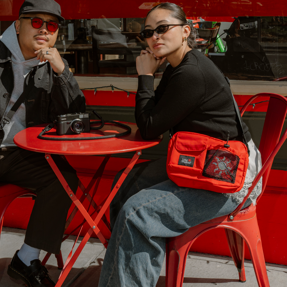 Red fabric shoulder bag with zip front pocket and adjustable crossbody strap.