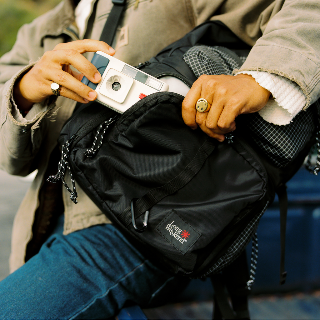 Black convertible backpack close-up: front pocket, zippers, and chain pull