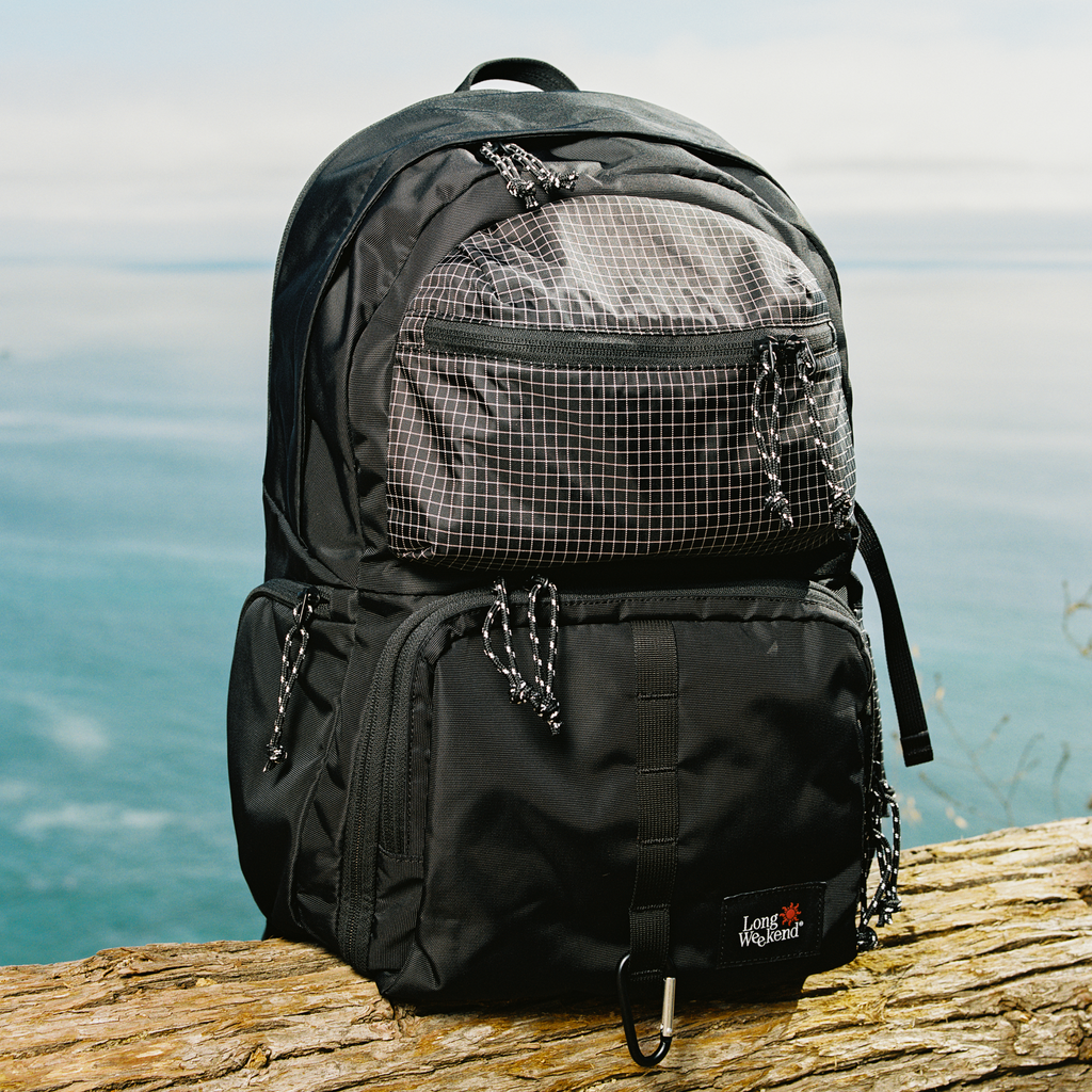Black convertible backpack standing on rock, large front panel and top handle