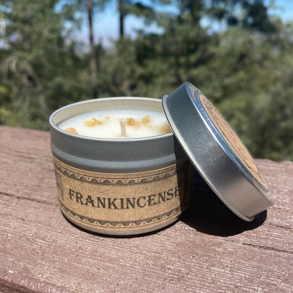 Open travel candle tin with white candle and blue-tinted silver lid, tan Frankincense band