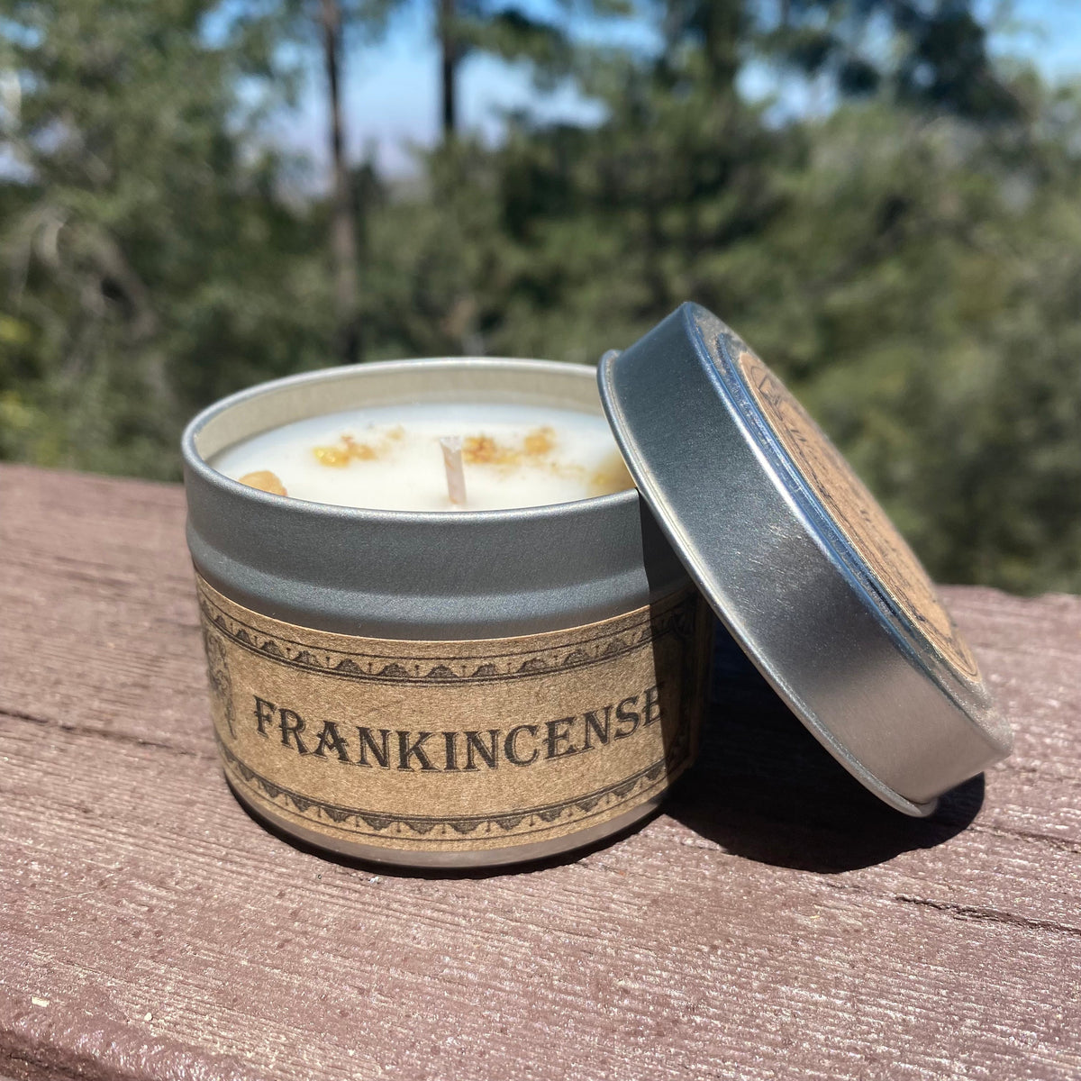 Open travel candle tin with white candle and blue-tinted silver lid, tan Frankincense band