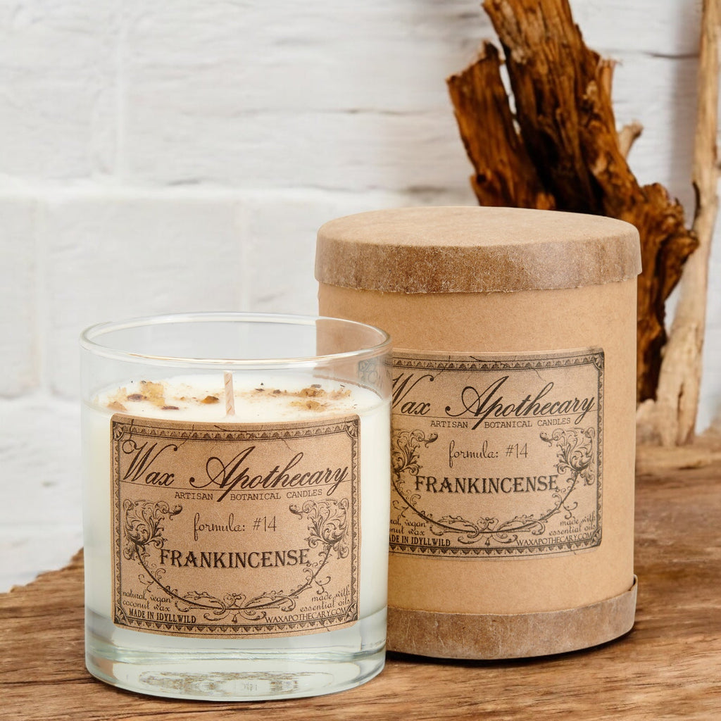 Frankincense botanical candle in clear scotch glass with kraft label, burning wick visible