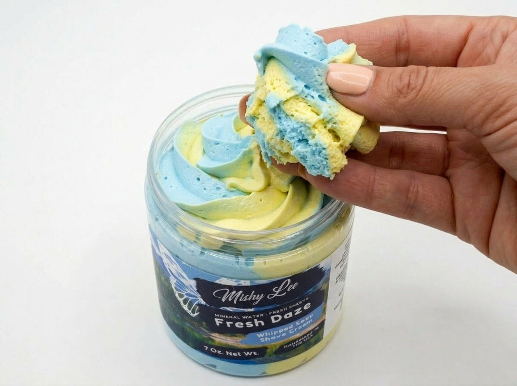 Hand holding a scoop of blue and yellow whipped soap and shave cream