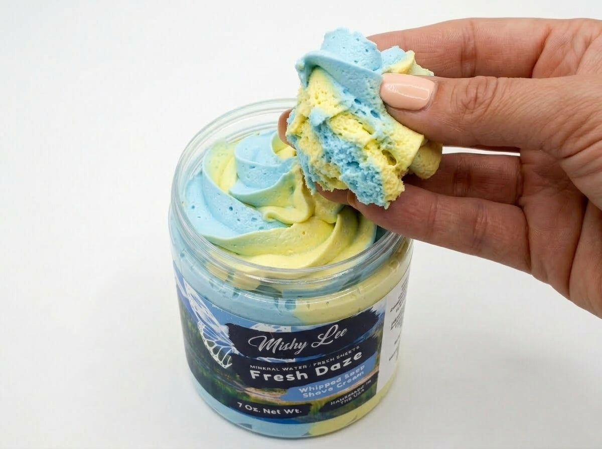 Hand holding a scoop of blue and yellow whipped soap and shave cream