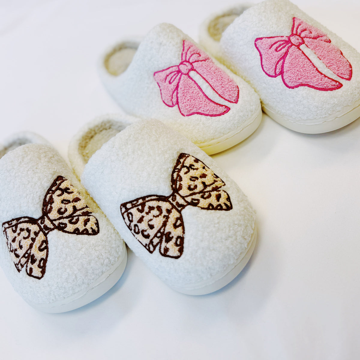 Assorted bow slippers in cream with pink and leopard-print bow designs