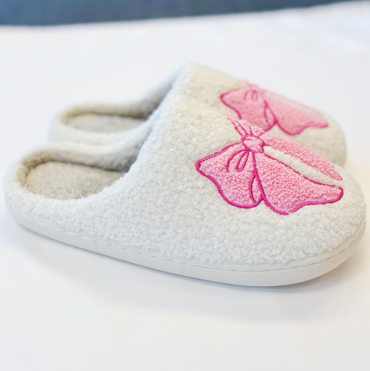 Single cream cozy slipper with pink bow applique and cushioned plush lining