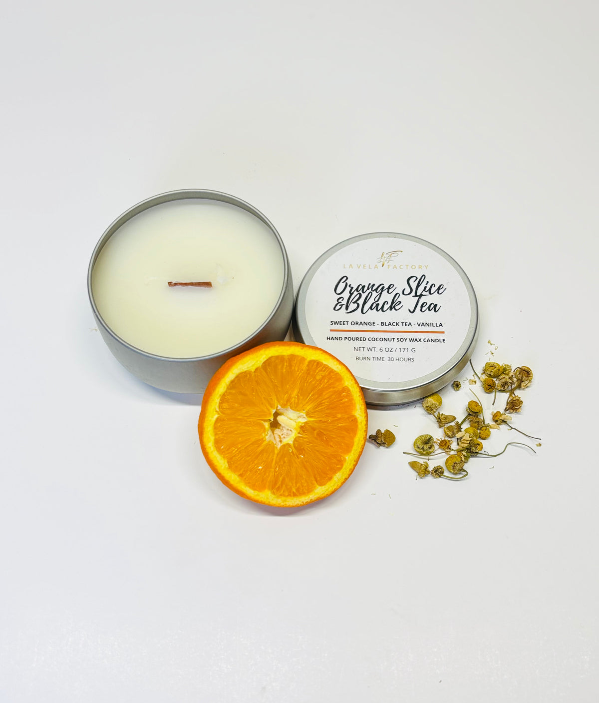 Wood-wick candle in gray tin; lid labeled Orange Slice & Black Tea with orange slice.
