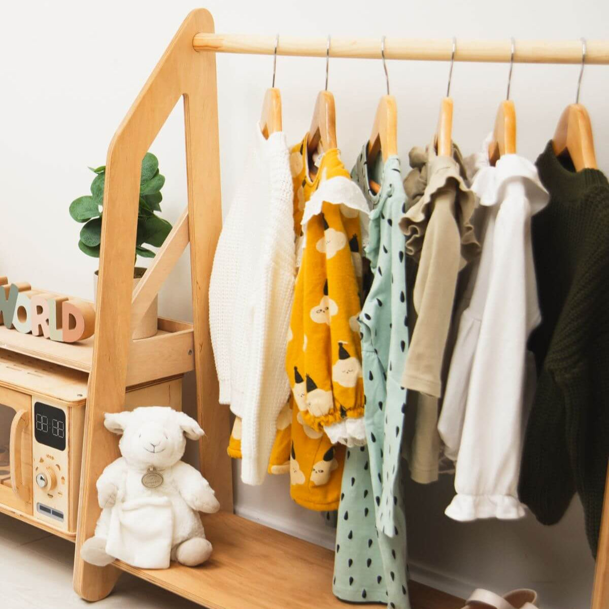 Light wood organizer with hanging clothing rack and open side shelves for toys