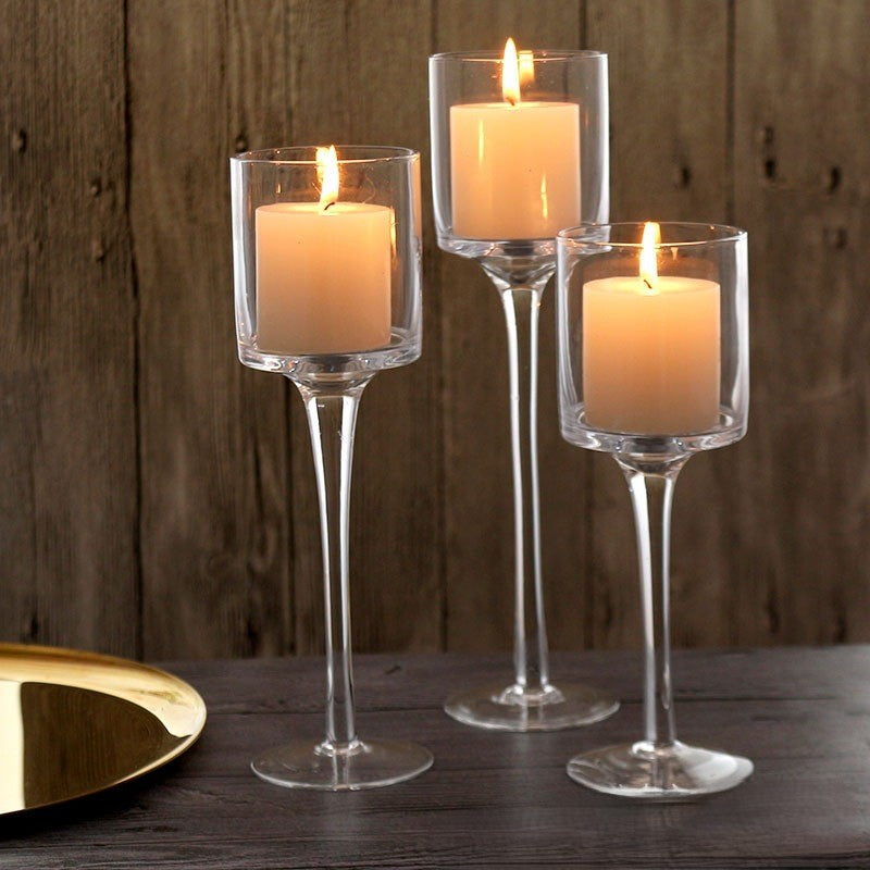 Set of 3 clear glass tapered pedestal holders with lit candles