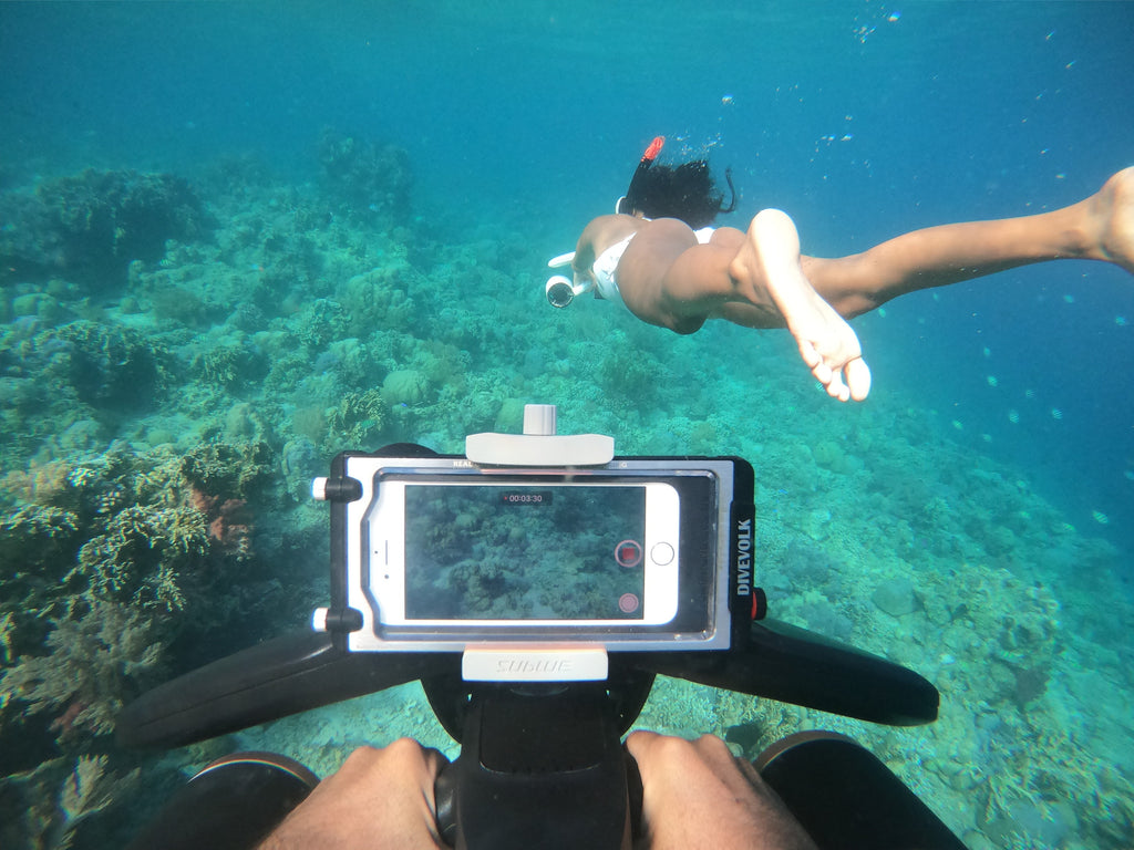 Handheld underwater camera with white-and-black frame pointed at scenery