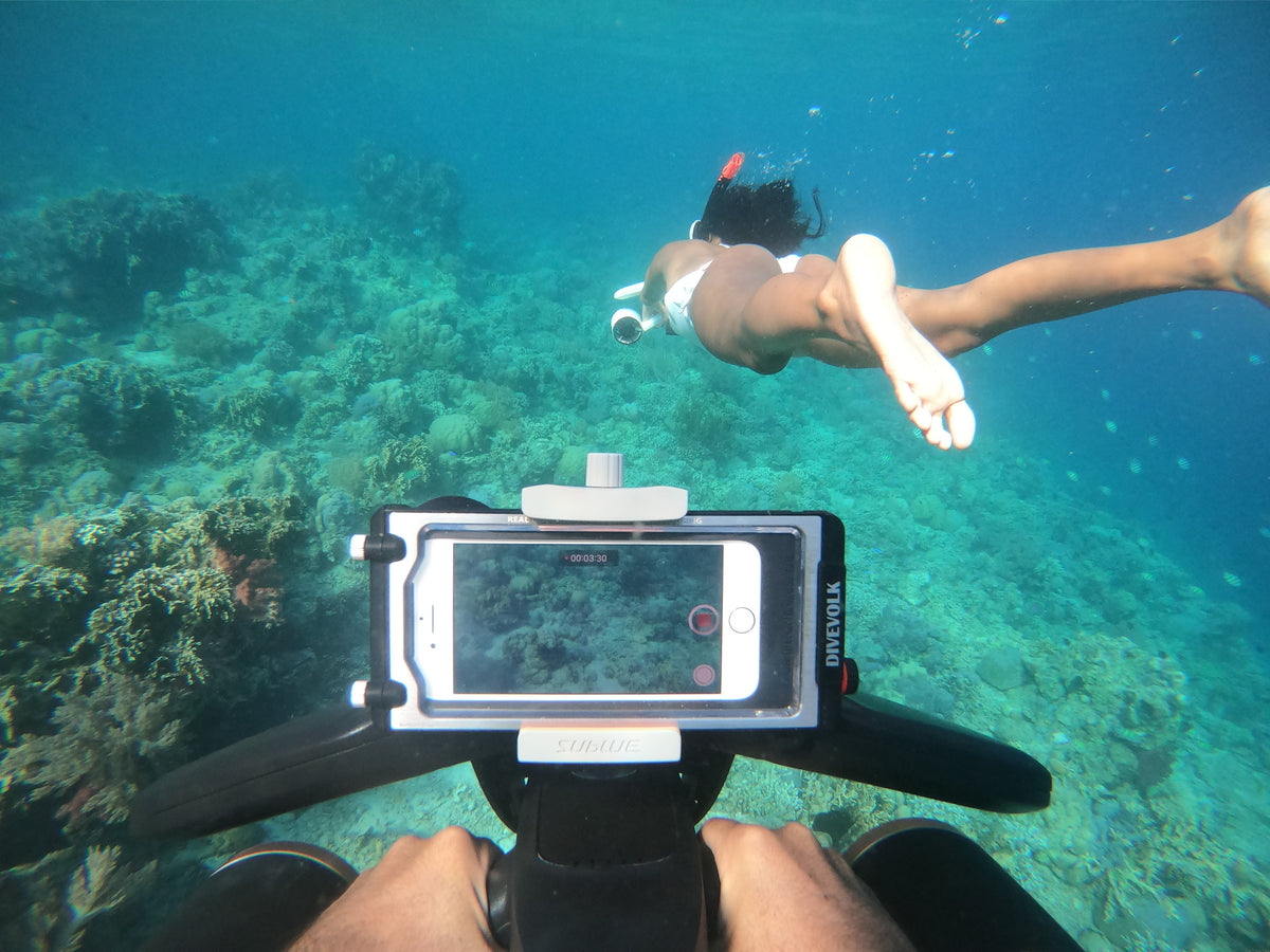 Handheld underwater camera with white-and-black frame pointed at scenery