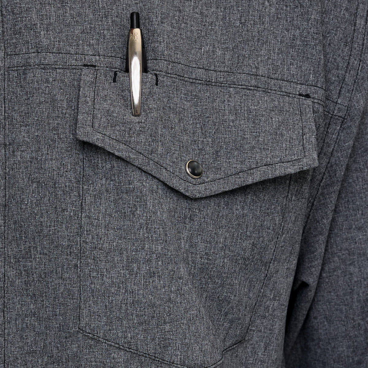 Dark gray shirt chest pocket with snap-button flap and metal buttons