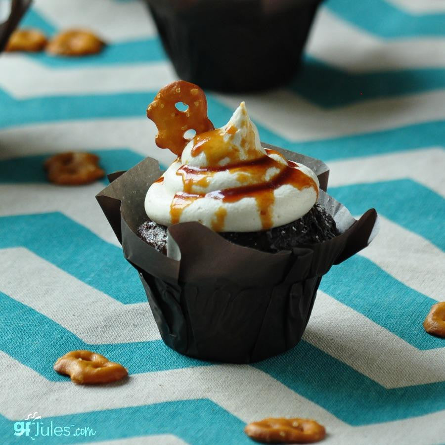 Gluten-free flour cupcake with white frosting and caramel drizzle in a black liner