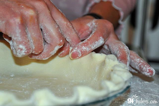 Gluten-free flour dough being kneaded on a floured surface by bare hands