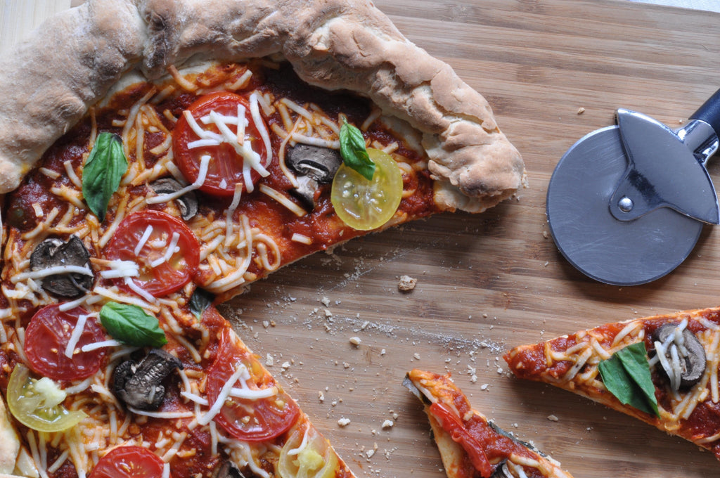 Gluten-free pizza crust slice with pepperoni, olives, mushrooms, and basil