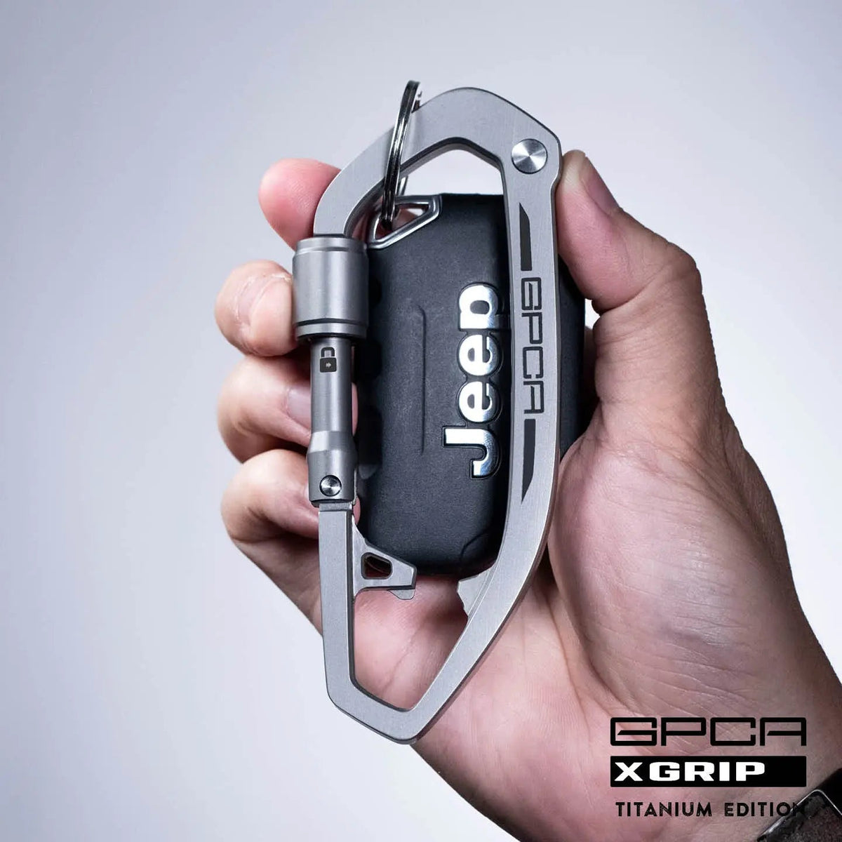 Dog leash carabiner clip with gray metal body and black strap, held in hand.