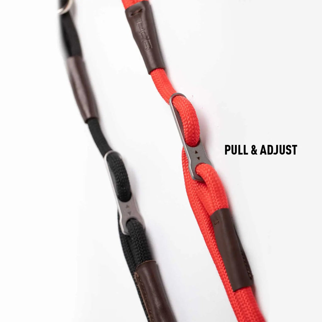 Dog leash with red and brown sections and black handle grips for pull and adjust.