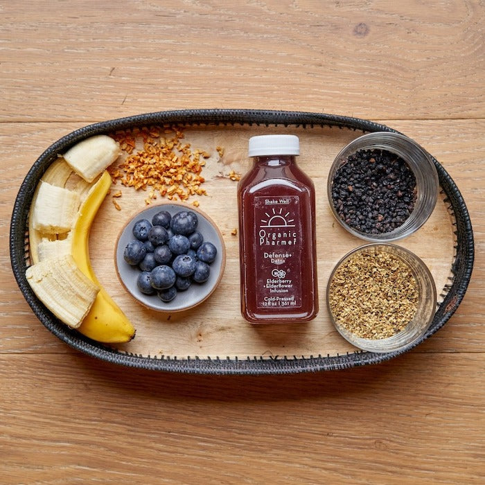 Protein shake bottle with tray of banana, blueberries, and seed blend ingredients