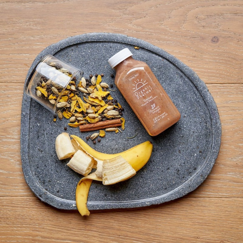 Organic protein shake bottle with banana, granola, and spices on dark plate