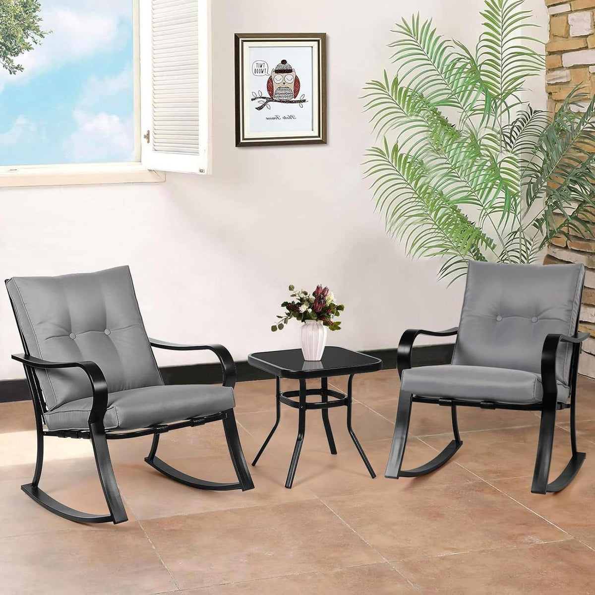 Patio seating set with two grey rocking chairs, a black square table, and vase