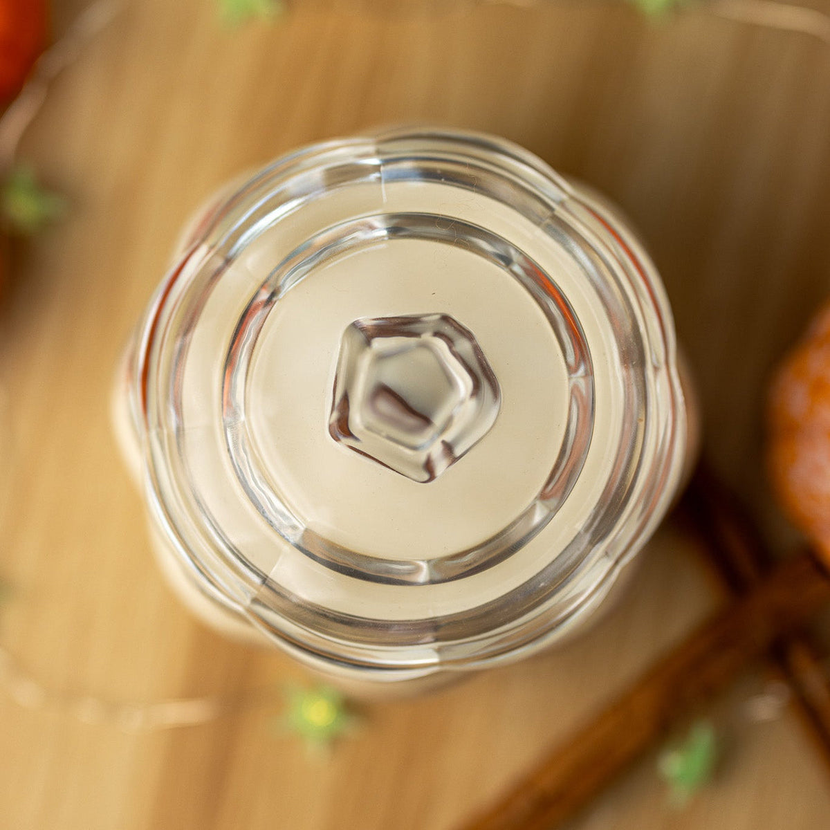 Top view of clear glass candle jar lid and cream wax surface with wick