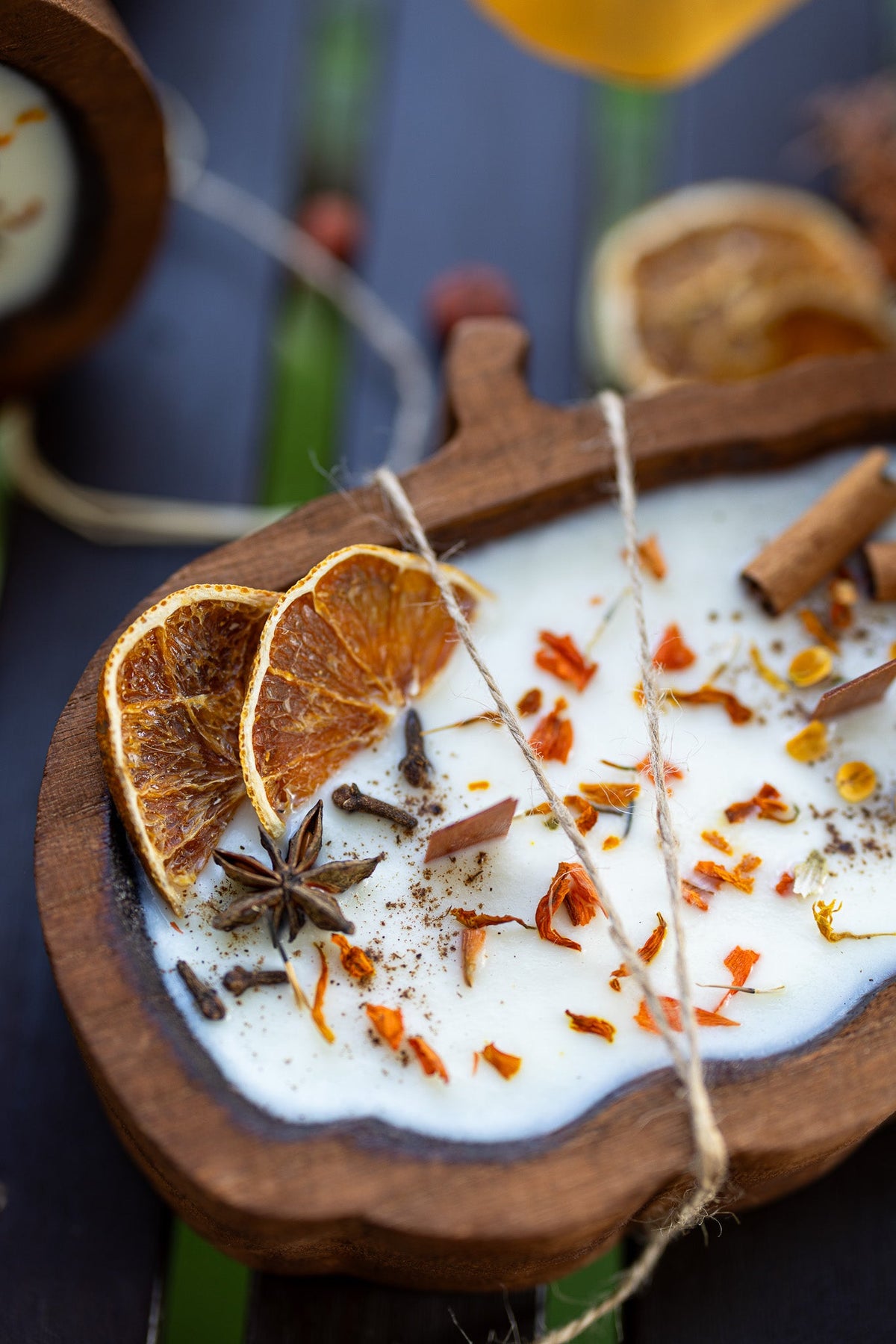 Wooden pumpkin-shaped dough bowl candle with orange slice, star anise, and spice flakes