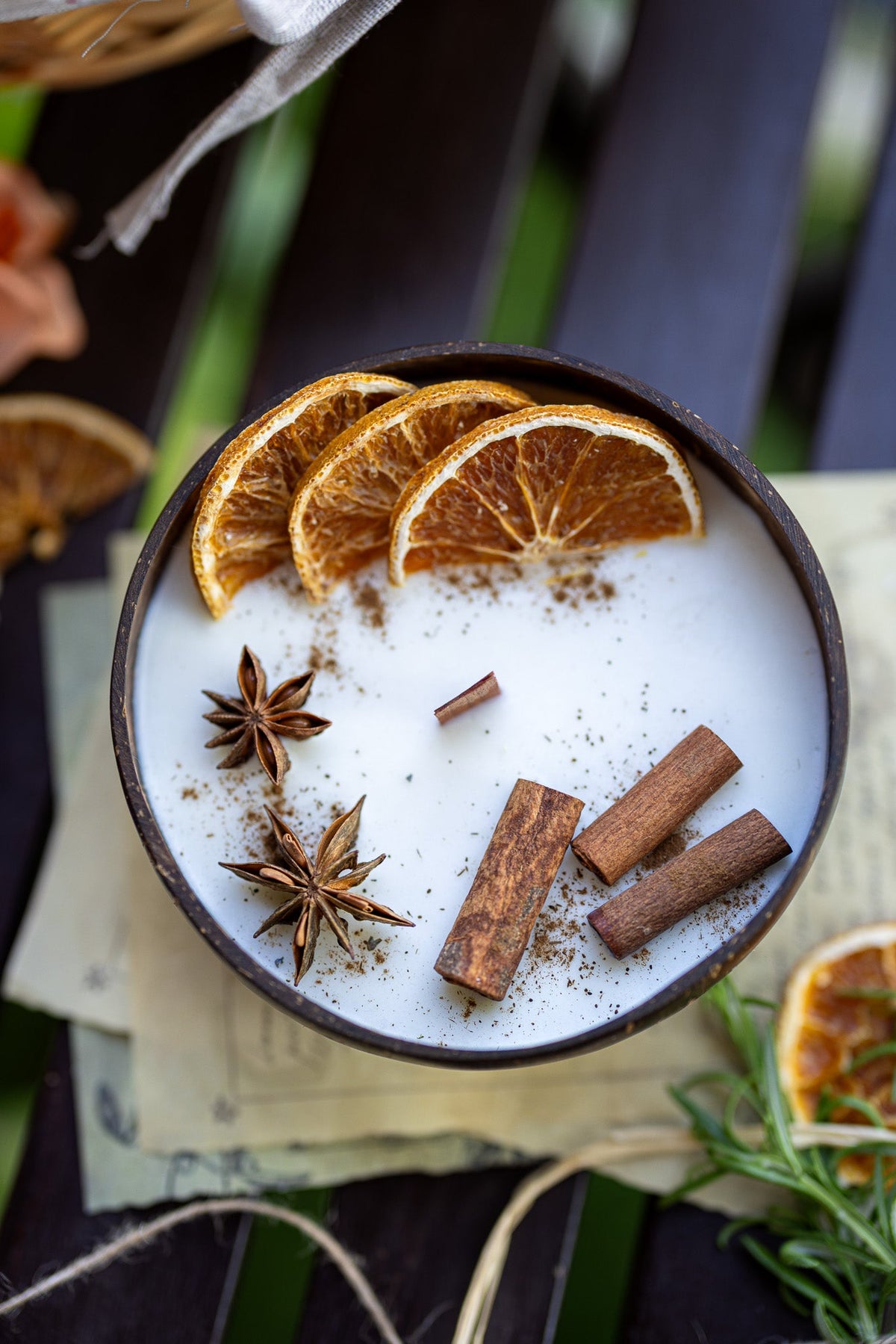 Scented candle in dark bowl: white wax with orange slices, cinnamon sticks, star anise