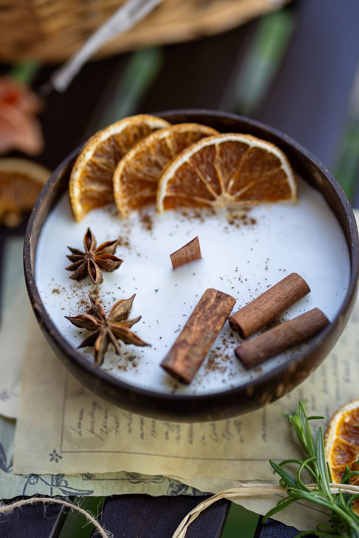 Scented candle bowl with white wax, orange slices, cinnamon sticks, and star anise
